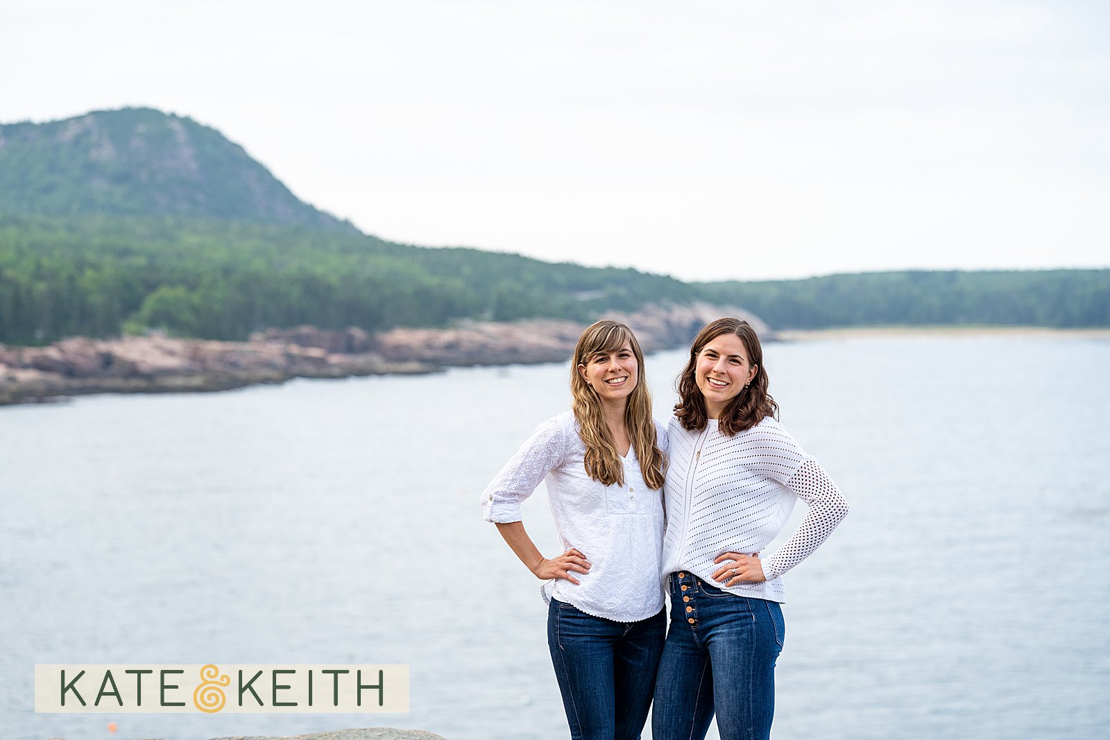 adult twin sisters posing on rocks with Acadia National Park as a backdrop