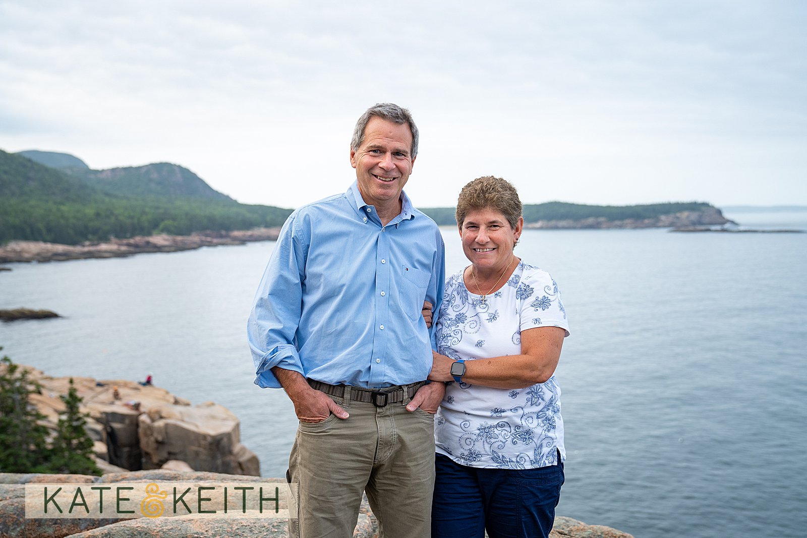 husband and wife posing on the coastline of Acadia National Park