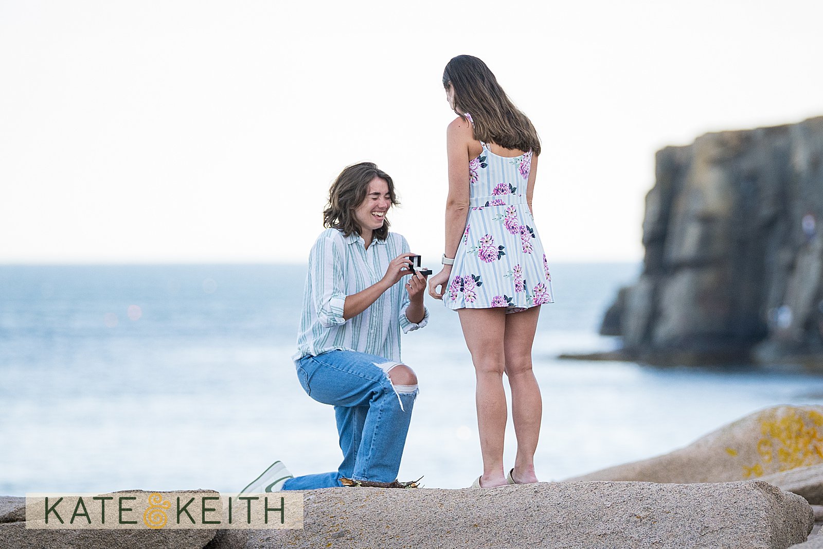 woman on one knee proposing to her girlfriend in Acadia National Park, with cliff and ocean in the background