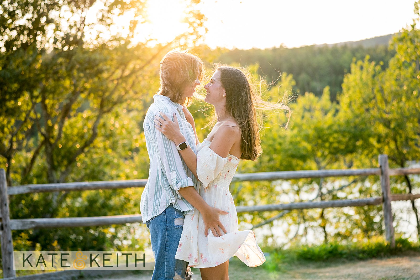 two women embracing on a windy summer day among trees, ocean and a setting sun