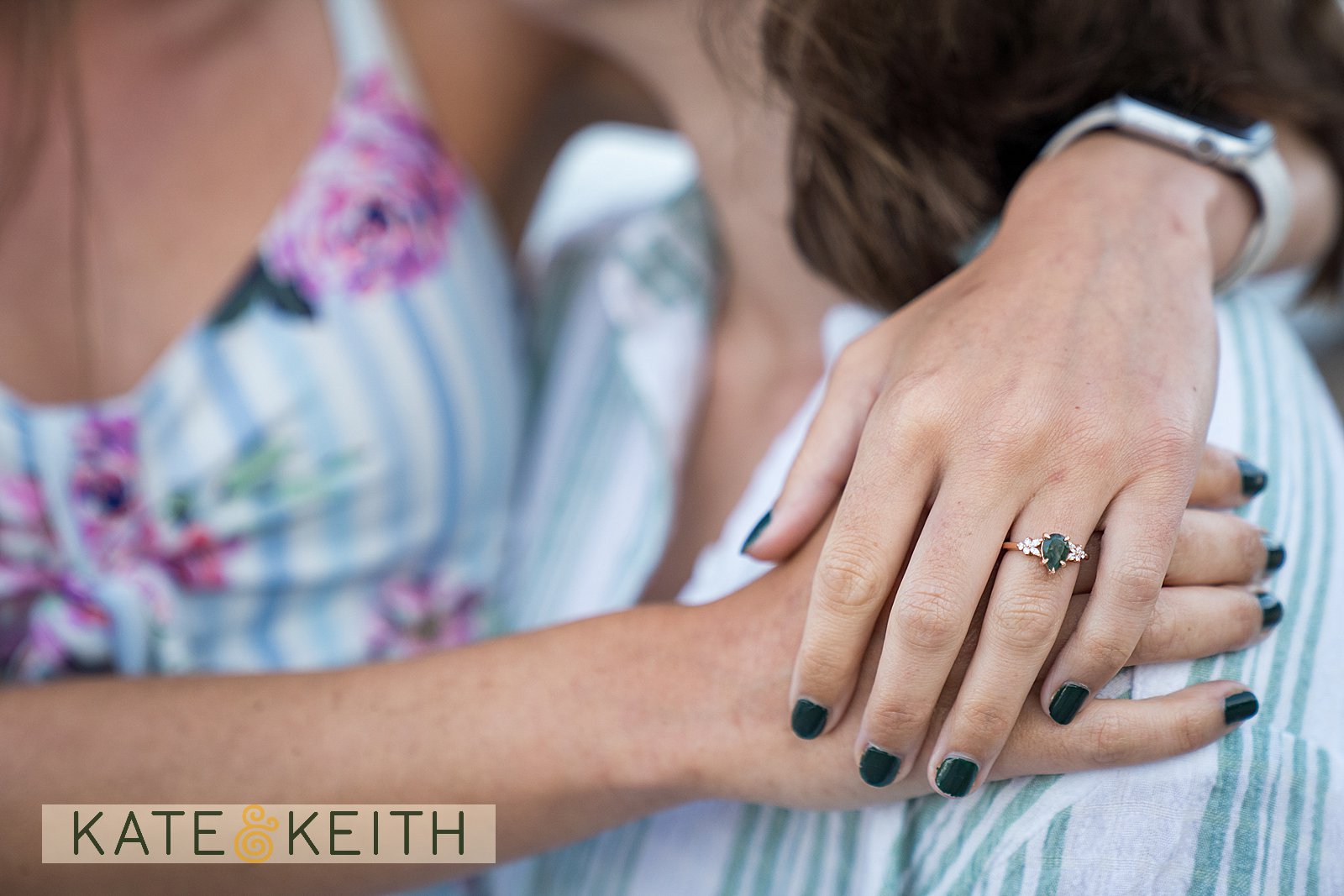 close up of an engagement ring on a woman's hand as her arms are wrapped around her fiance