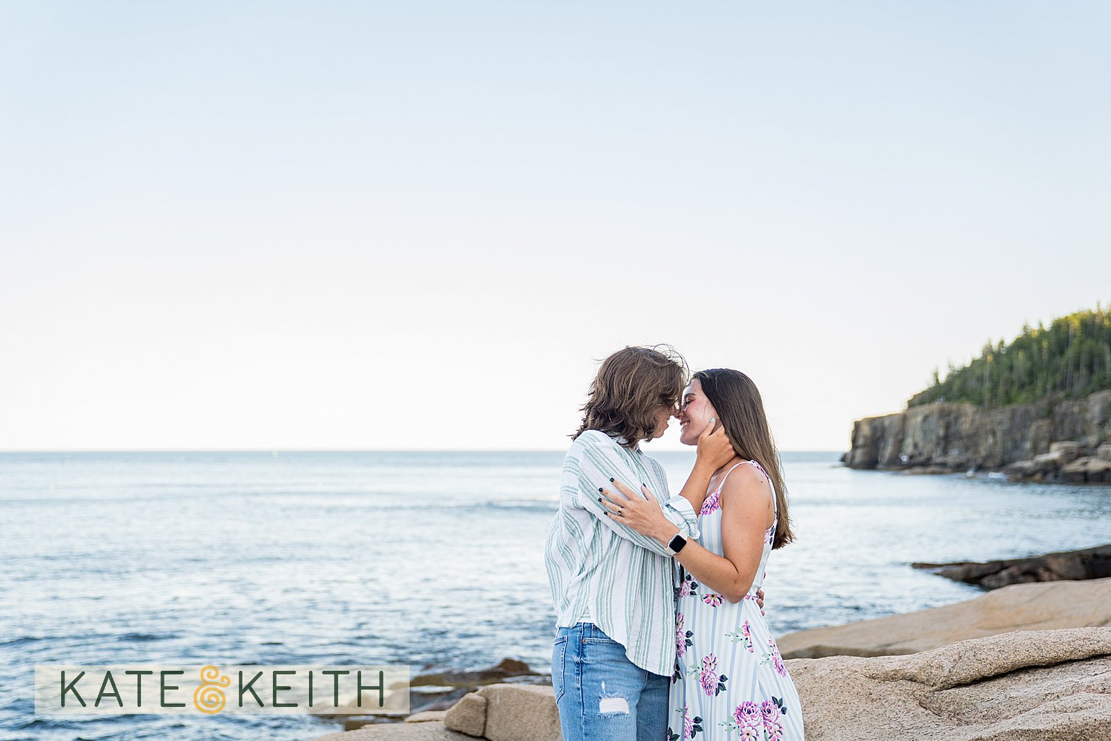 a landscape photo of the Acadia National Park coastline with two women embracing during an engagement photo session
