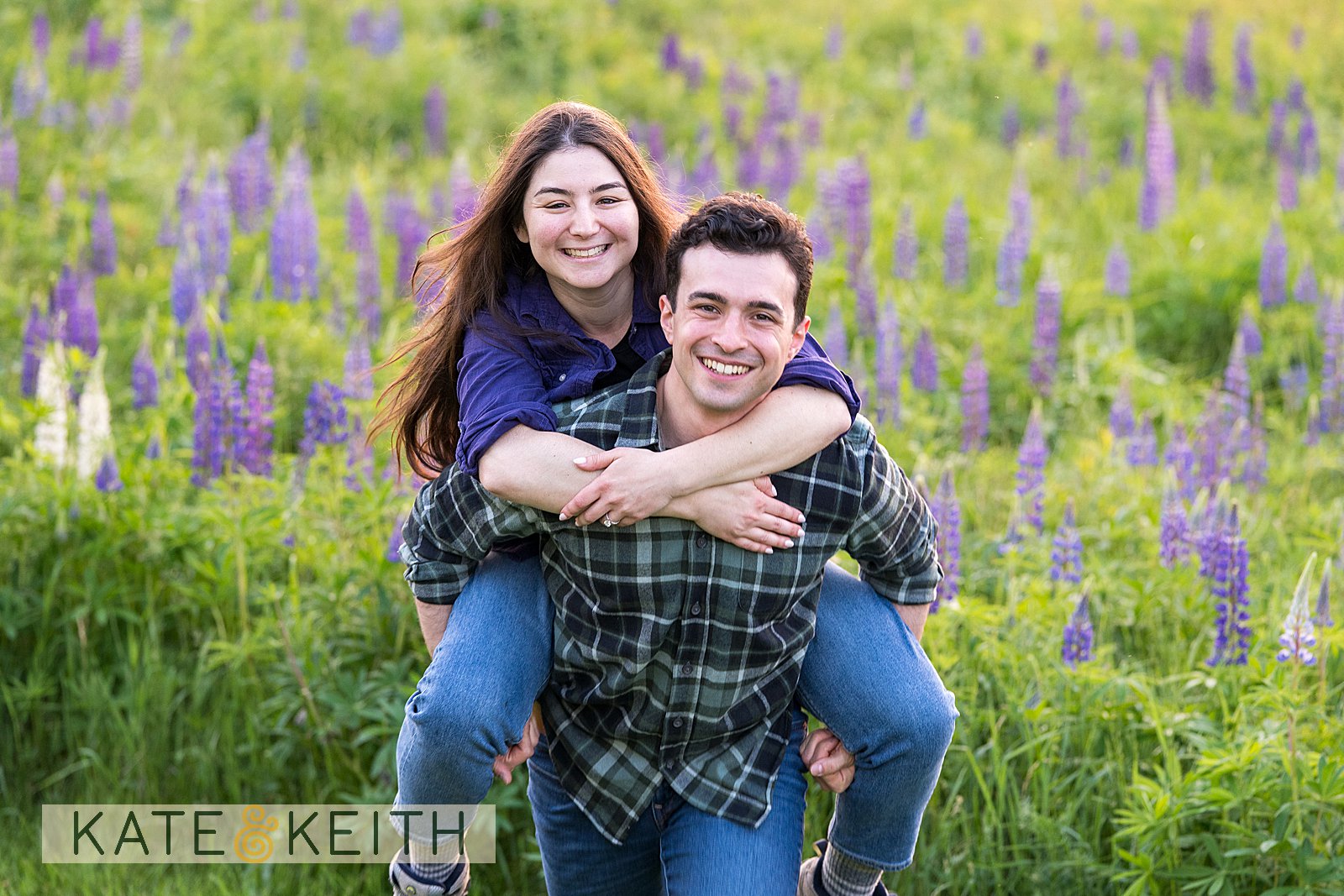 Couple piggybacking in wild lupine field of Acadia National Park